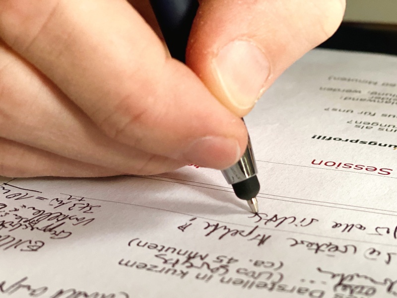 Nahaufnahme einer Hand mit Stift beim Arbeiten an Notizen